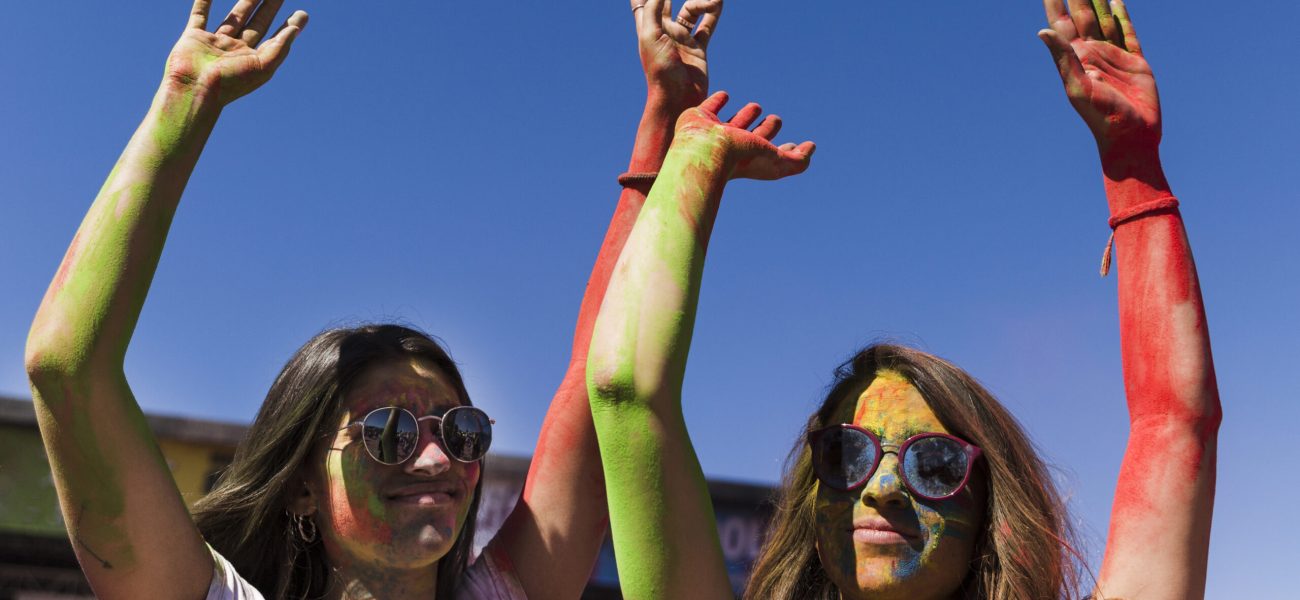 jeunes-femmes-portant-des-lunettes-de-soleil-profitant-du-festival-de-holi-sur-ciel-bleu